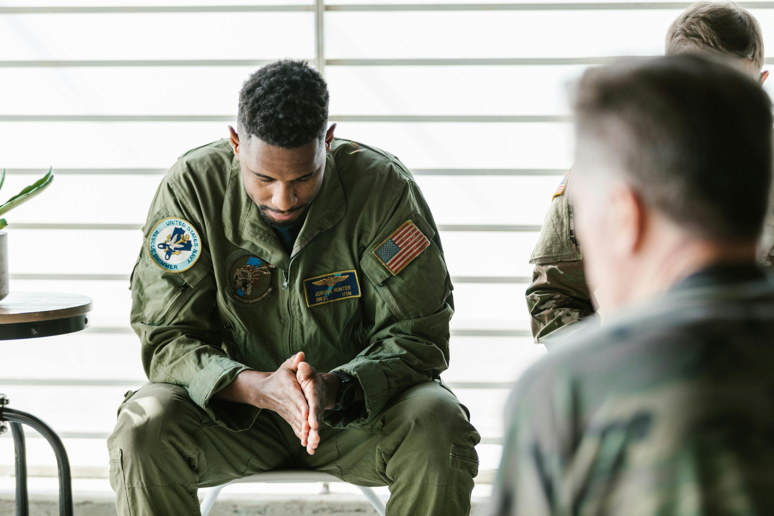 man wearing military uniform with his head down, looking at his hands